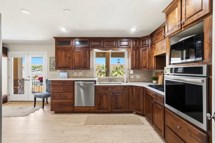 Kitchen featuring rich wood cabinetry, stainless steel appliances, light-toned countertops, tile backsplash, and wood-finish flooring