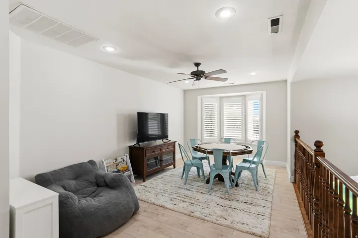 Bright open space featuring light wood-finish flooring and a bay window with plantation shutters