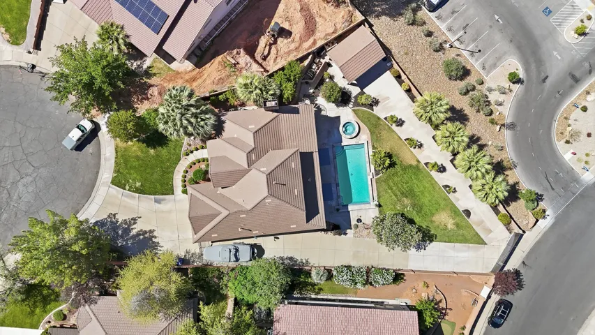 Expansive property featuring a multi-gabled roofline, a private swimming pool with an integrated spa, a manicured lawn, and mature landscaping