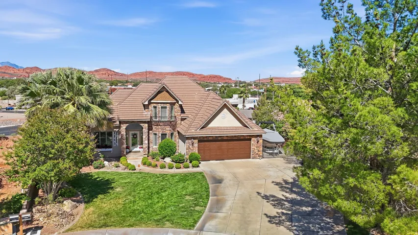 Stone and stucco exterior featuring a tile roof, arched entry, and an attached two-car garage with a wood-finish door