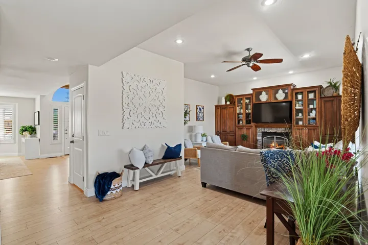 Bright living area featuring wood-finish flooring, a built-in media center with a stone-surround fireplace, recessed lighting, and a ceiling fan