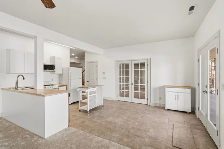 Open-concept living area with a kitchen featuring white cabinetry and wood-finish countertops