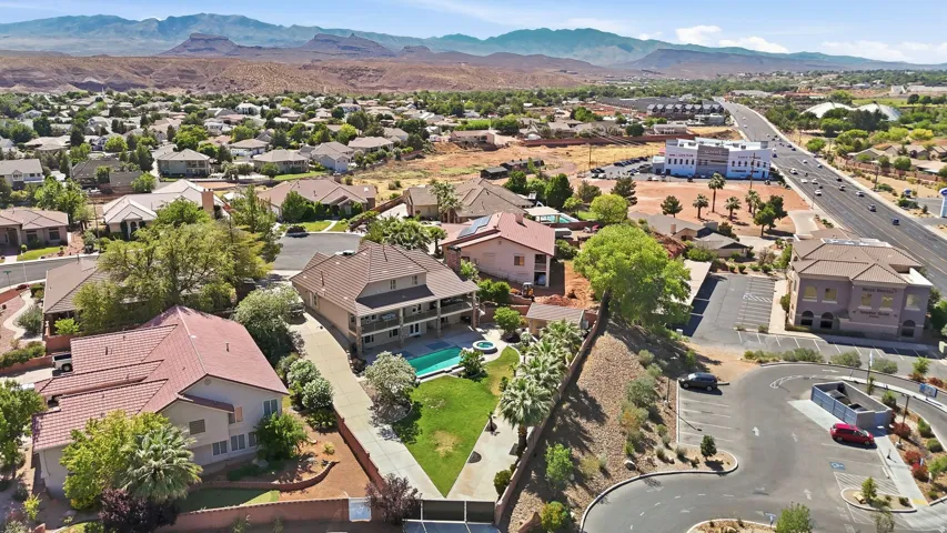 Two-story property featuring a pool, expansive lawn, mature trees, and a concrete driveway