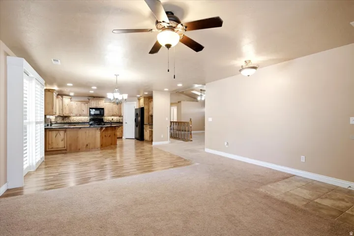 Open-concept interior featuring wood-finish flooring, recessed lighting, ceiling fan, and a kitchen with wood cabinetry and dark countertops
