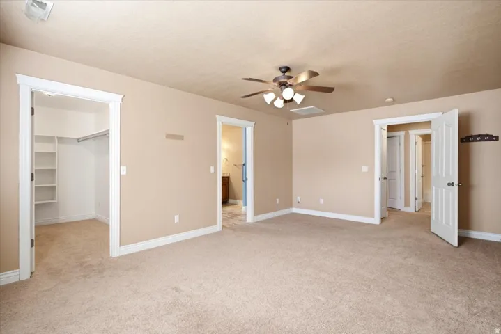 Carpeted room with a ceiling fan, recessed lighting, and a walk-in closet featuring built-in shelving and a clothing rod