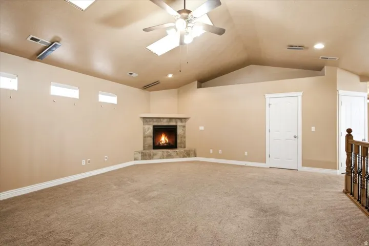 Spacious room featuring vaulted ceilings, a ceiling fan, and recessed lighting