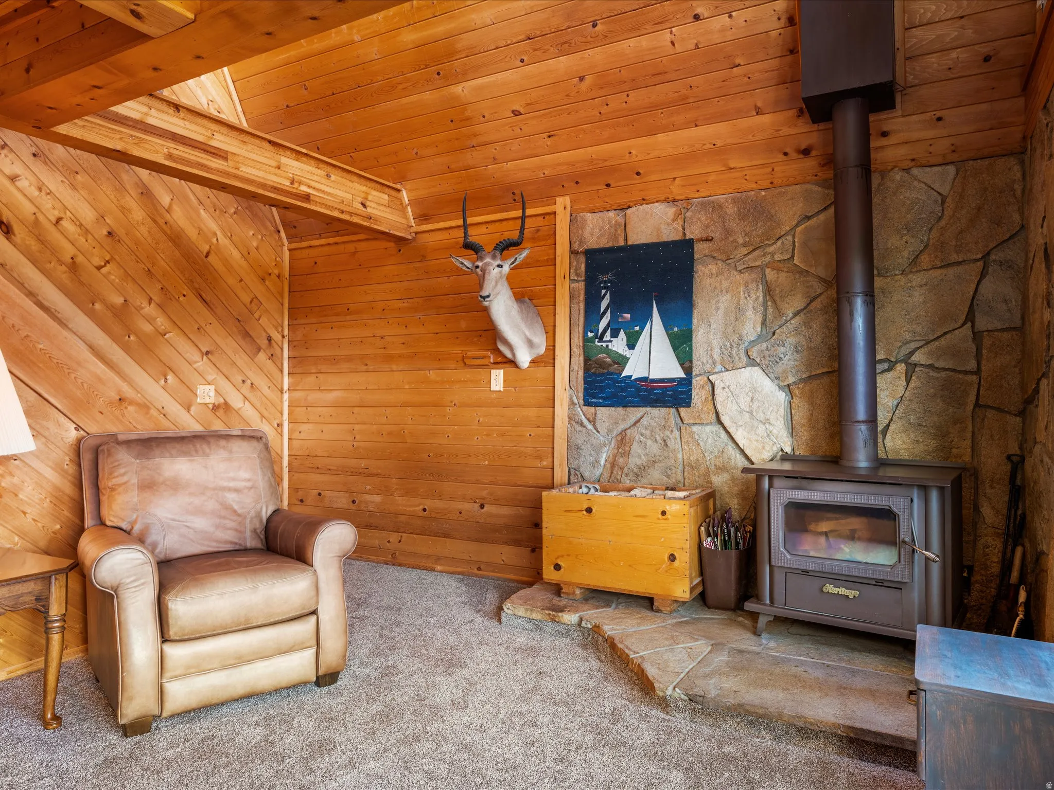 Wood-paneled room with a stone accent wall, featuring a wood-burning stove on a flagstone hearth