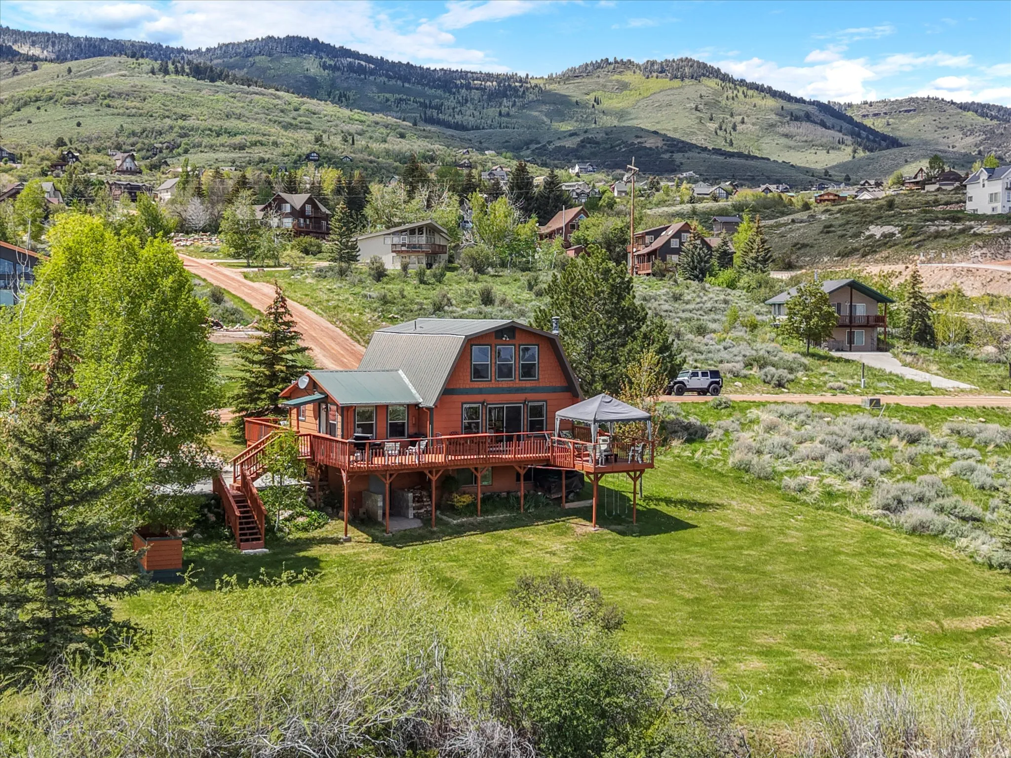 Mountain-style home featuring multiple levels of wood decking, a covered gazebo, and a metal roof