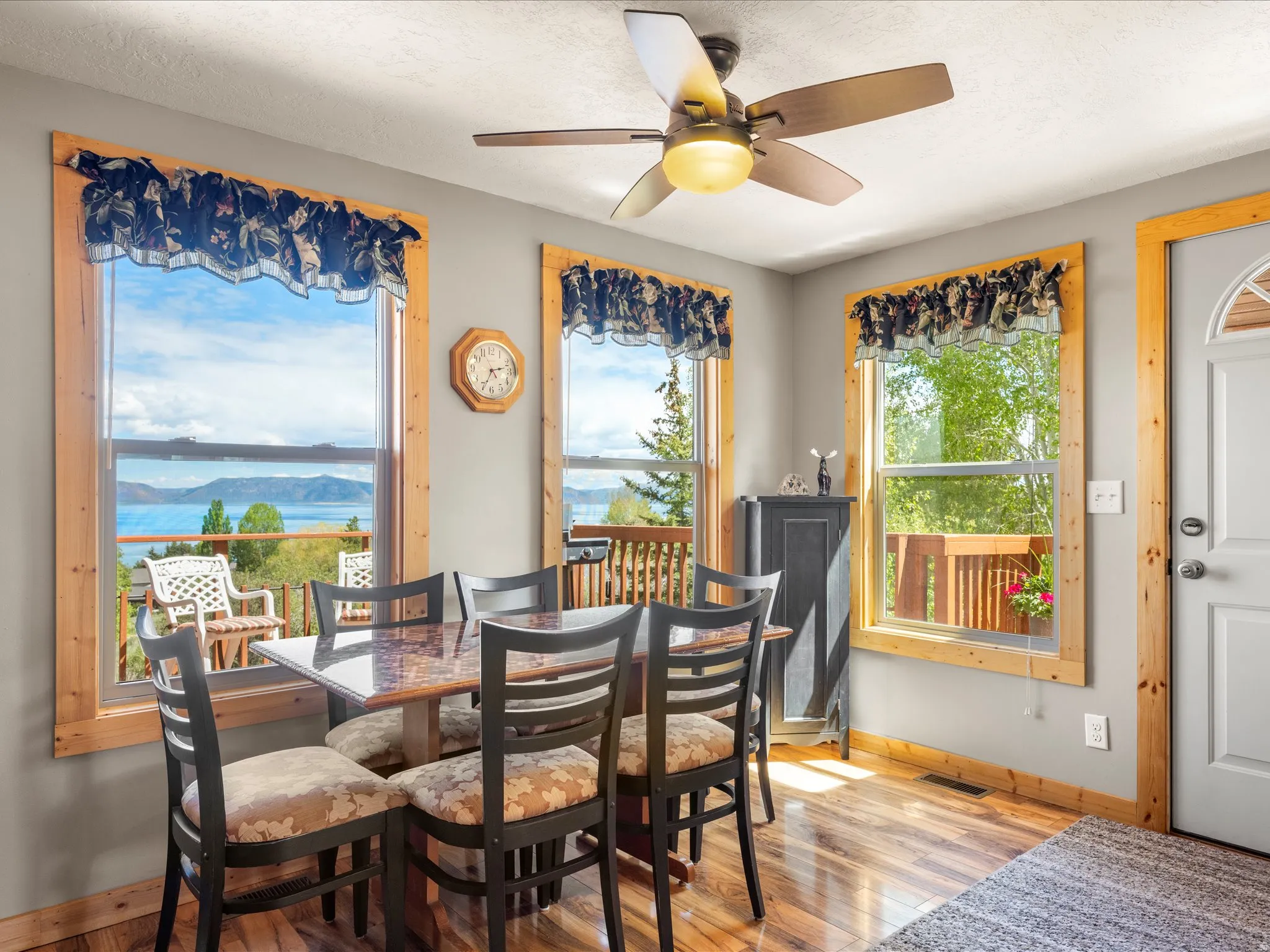 Dining area featuring wood-finish flooring, a ceiling fan with integrated lighting, and multiple windows with natural wood trim