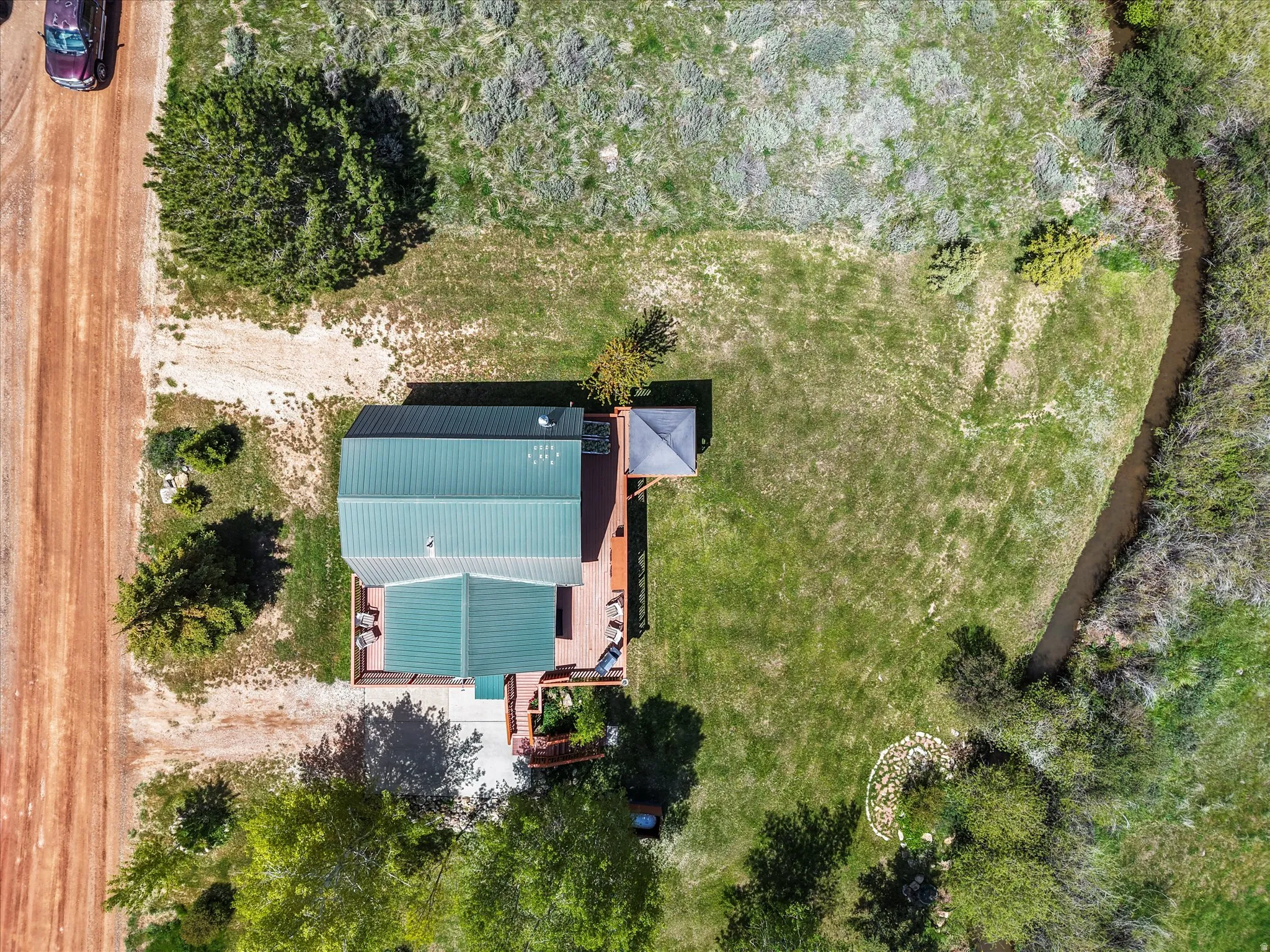 Aerial property overview featuring a dwelling with a green metal roof and extensive wood-finish decking
