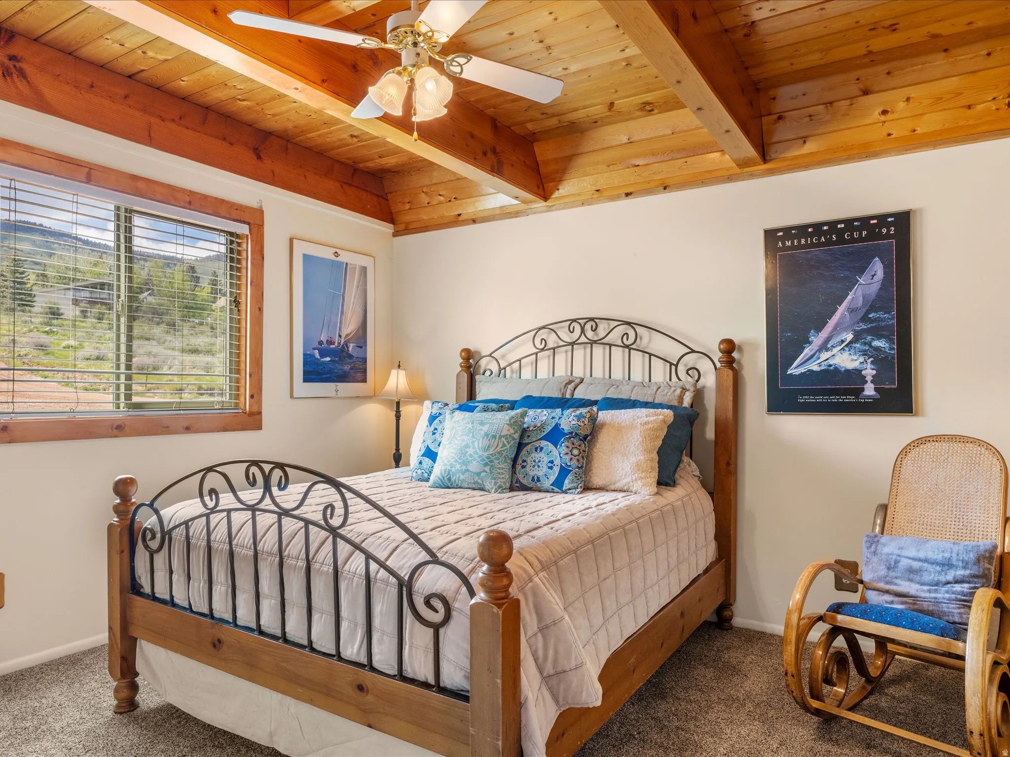 Bedroom featuring a vaulted wood-beam ceiling, wood-finish window trim, a ceiling fan with integrated lighting, and carpet flooring