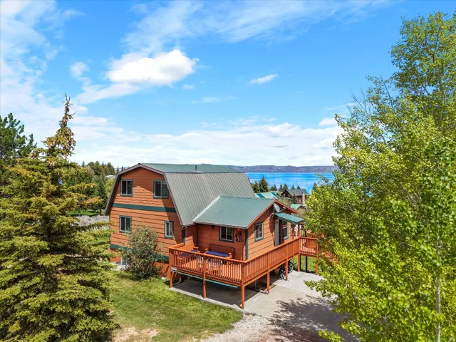 Property featuring wood siding, a green metal roof, and an expansive wood deck