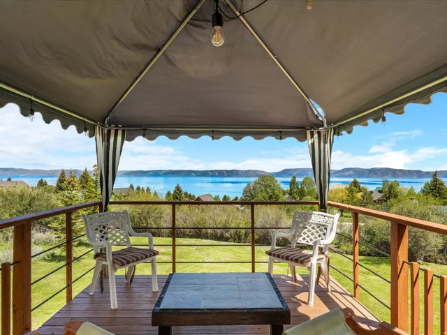 Wood-finish deck with a pergola-style canopy, offering expansive water scenery and distant mountains