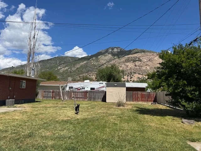 Expansive backyard featuring a mountain backdrop, mature trees, and a storage shed