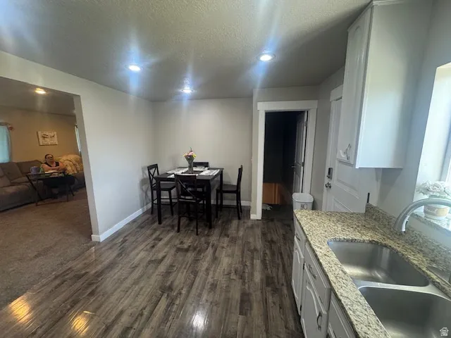 Kitchen featuring wood-finish flooring, granite-style countertops, an undermount double-basin sink with a gooseneck faucet, and white cabinetry