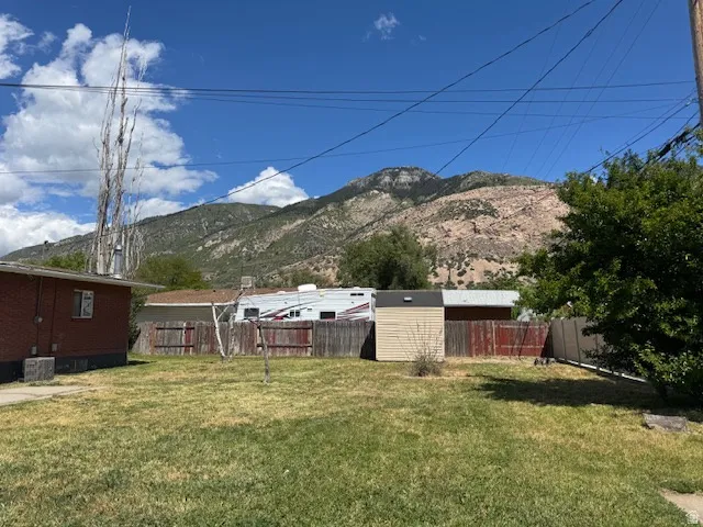 Expansive backyard featuring a grass lawn, wood fencing, and a utility shed