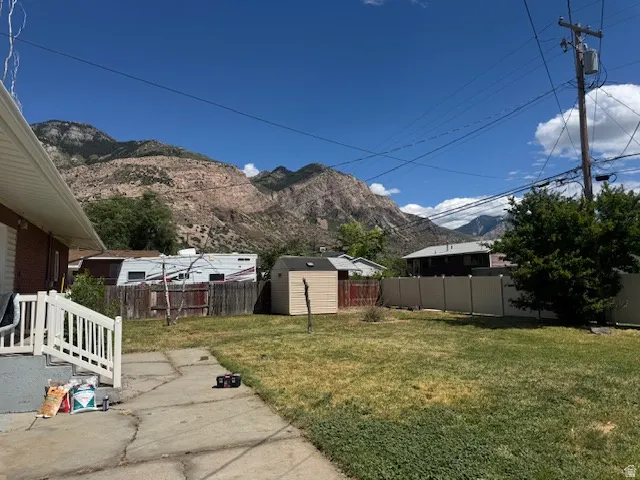 Expansive backyard featuring a concrete patio, a detached storage shed, and perimeter fencing