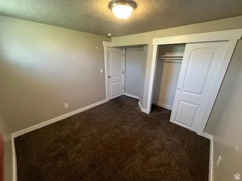 Bedroom featuring a neutral wall color, dark carpeting, and white baseboards