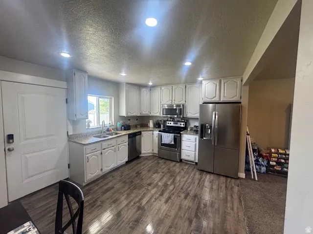 Kitchen featuring wood-finish flooring, white cabinetry, granite countertops, and recessed lighting