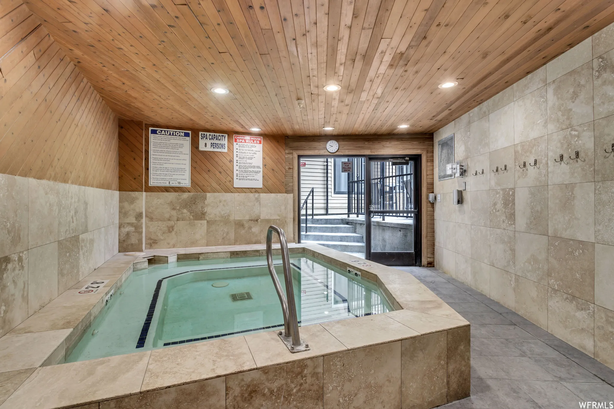 Indoor spa featuring a tiled surround, wood-finish ceiling, recessed lighting, and access to exterior stairs