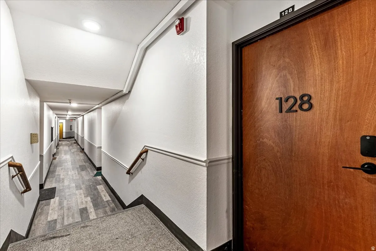 Entry corridor featuring a wood-finish door with modern hardware, recessed ceiling lighting, and wood-finish flooring