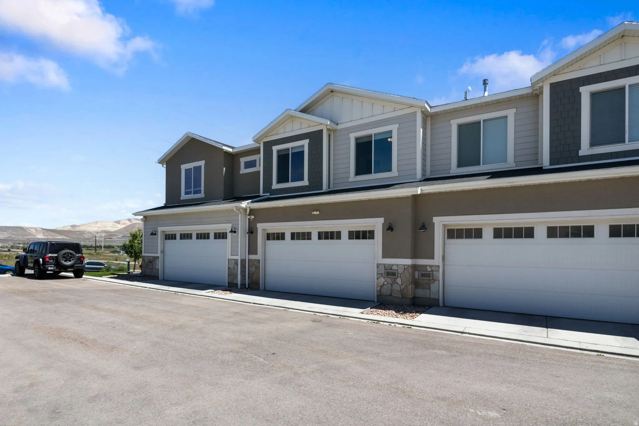 Modern townhome exteriors featuring neutral-toned stucco and siding, stone accents, and white trim