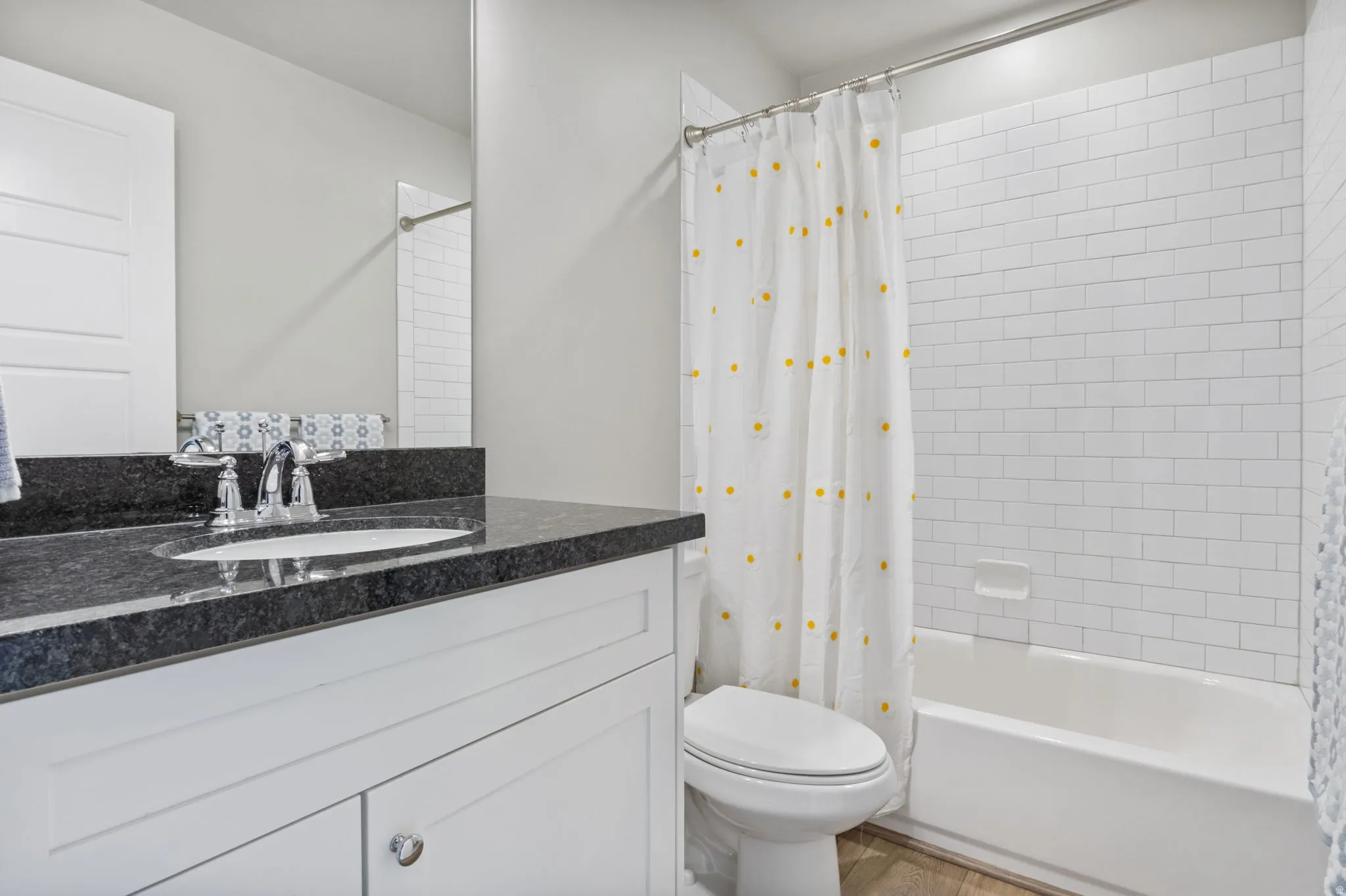 Bathroom featuring a white subway tile shower surround, a built-in tub, and wood-finish flooring