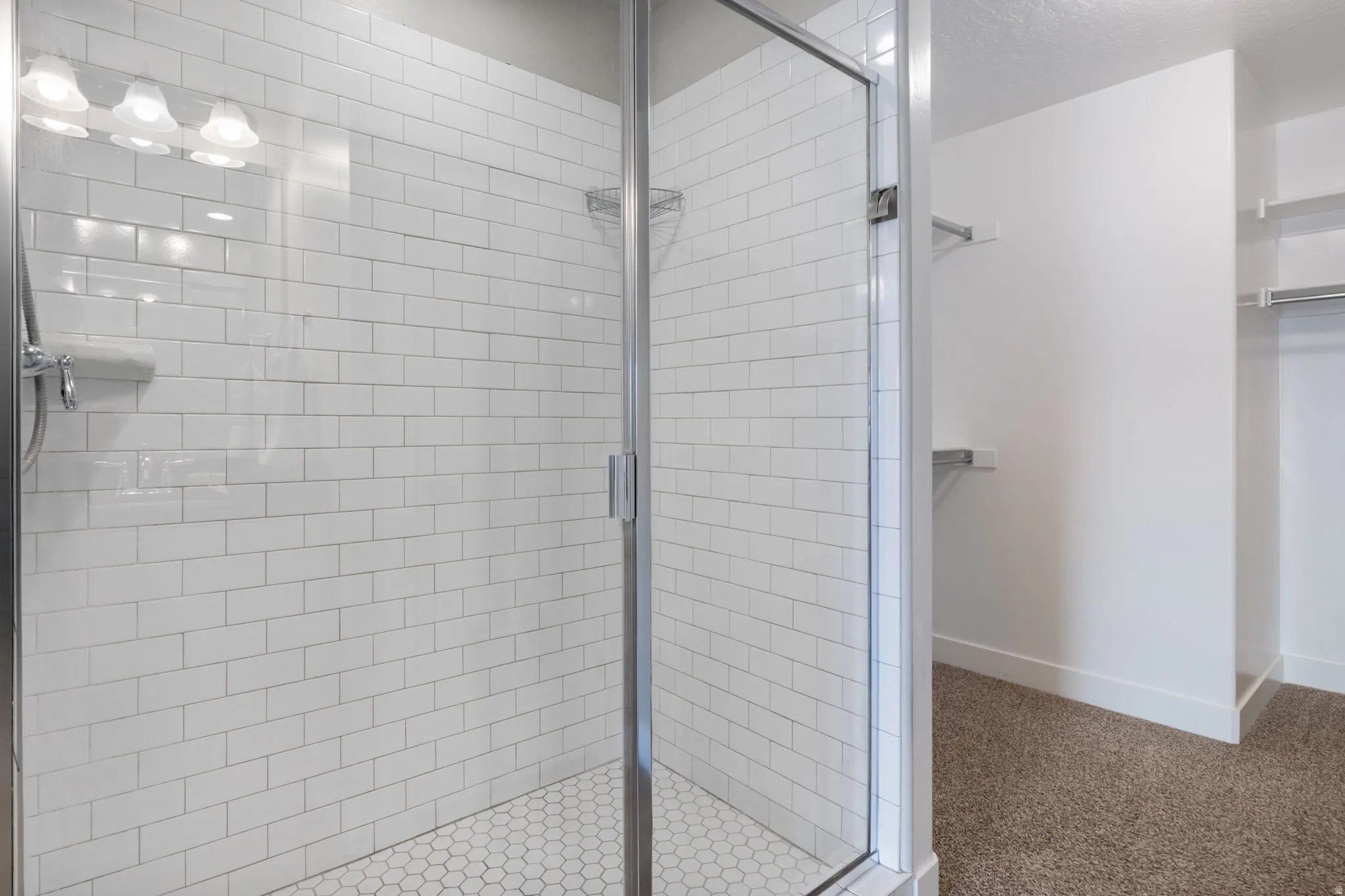 Enclosed shower with subway tile surround, hexagonal tile flooring, and integrated lighting