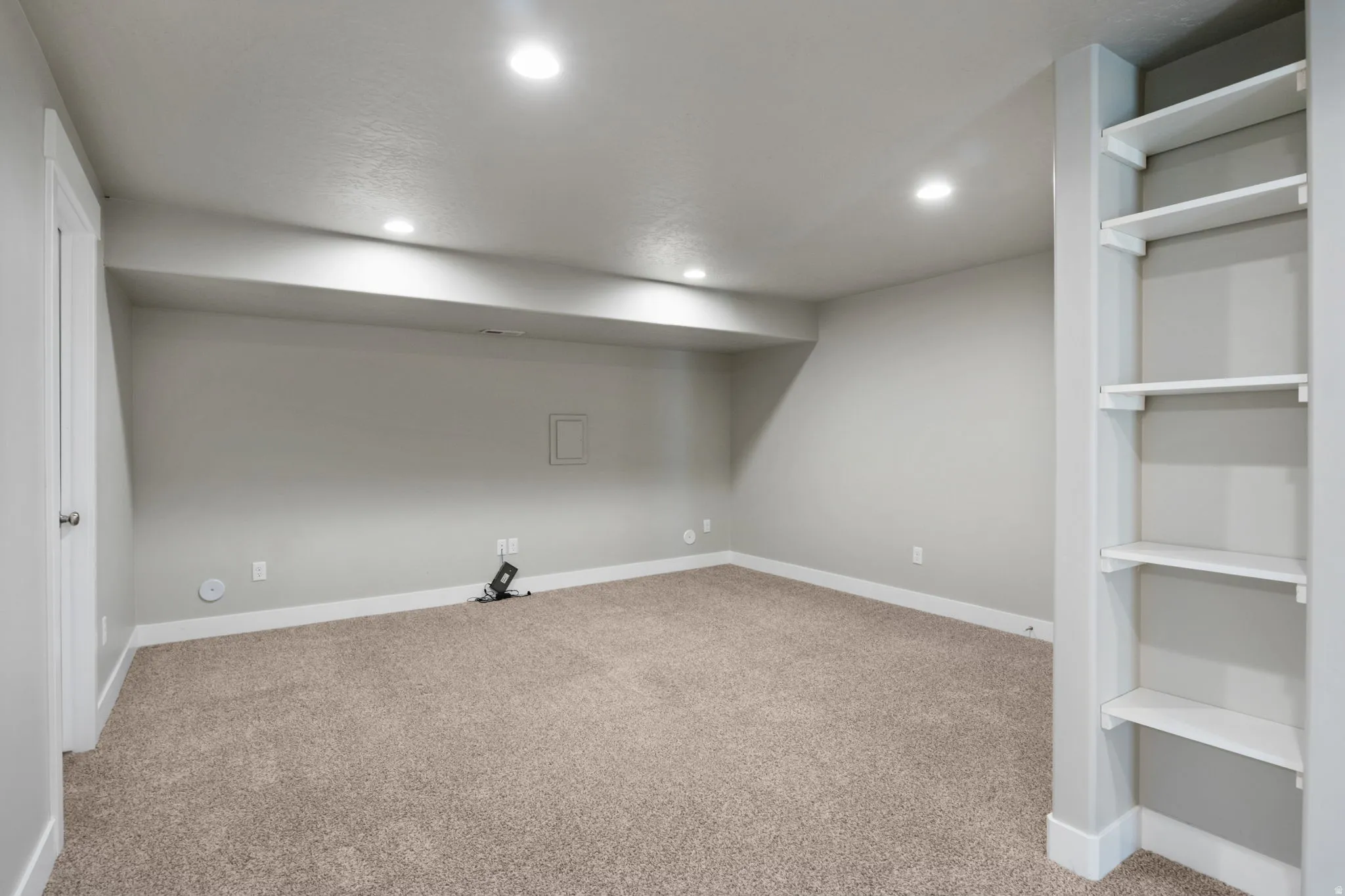 Spacious room featuring neutral carpeting, recessed lighting, and built-in shelving
