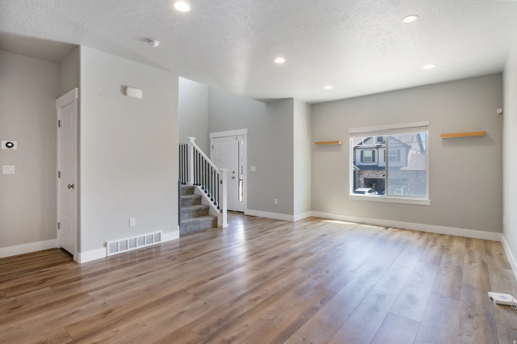 Spacious living area featuring wood-finish flooring, recessed lighting, and a large window