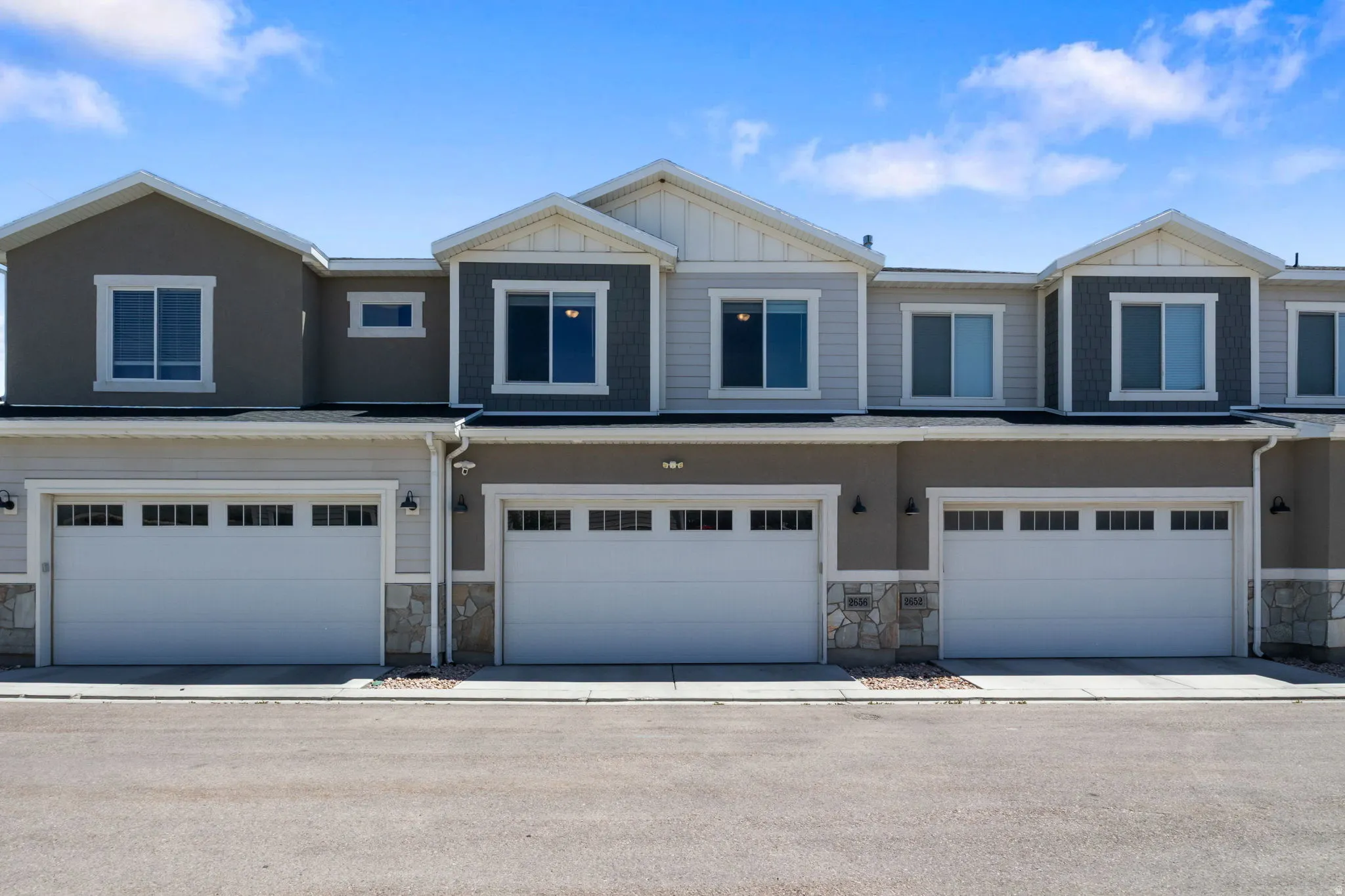 Modern townhome exteriors featuring multi-toned siding, stone accents, and integrated garages with windowed doors