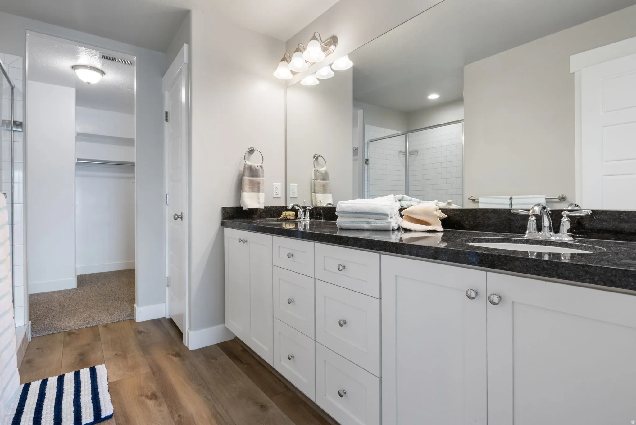 Bathroom featuring a double vanity with white cabinetry, dark granite countertop, and dual undermount sinks