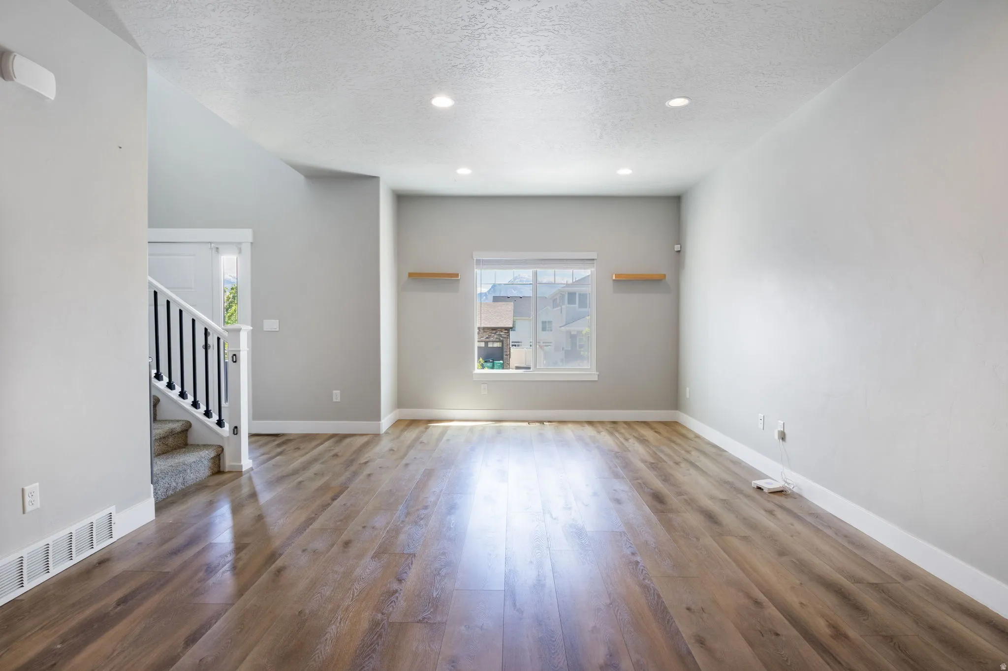 Open-concept living space with wood-finish flooring, recessed lighting, and a neutral color palette