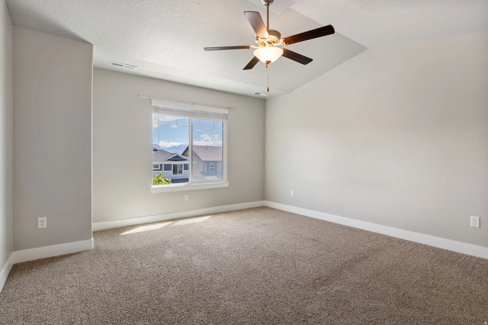 Spacious room with vaulted ceilings, recessed window, and neutral-toned carpeting