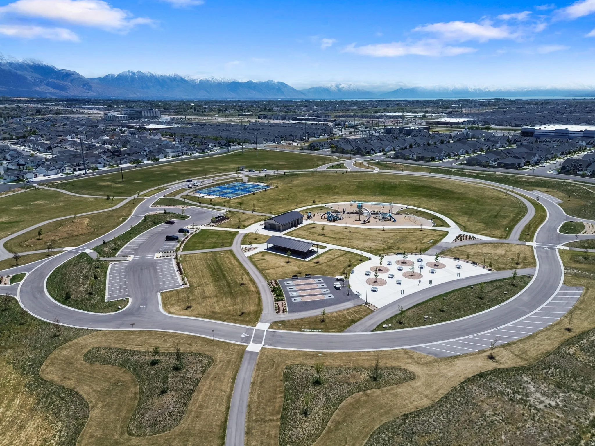 Community park featuring expansive green spaces, structured play areas, covered pavilions, sports courts, and convenient parking