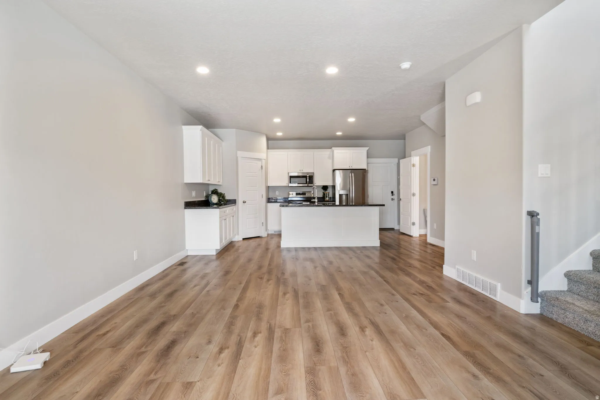 Open-concept living space with wood-finish flooring, recessed lighting, and light gray wall paint