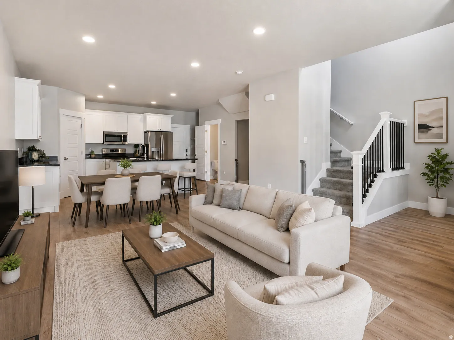 Open-concept living area featuring wood-finish flooring, a contemporary staircase with black spindles, and recessed lighting