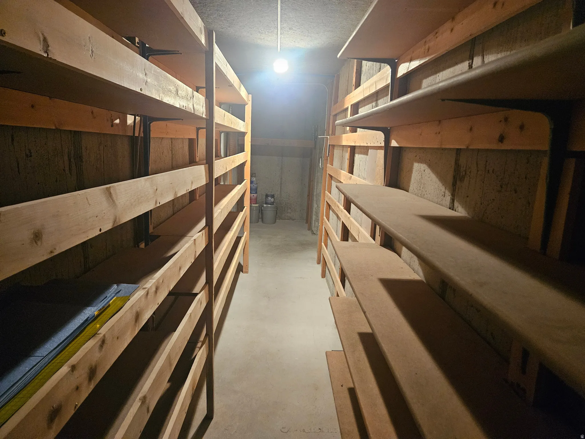 Dedicated storage room featuring concrete flooring and built-in wood shelving on both walls