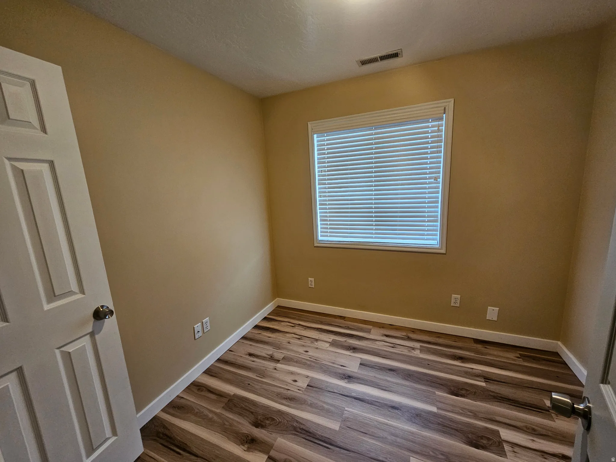 Room featuring wood-finish flooring, neutral wall tones, and white trim