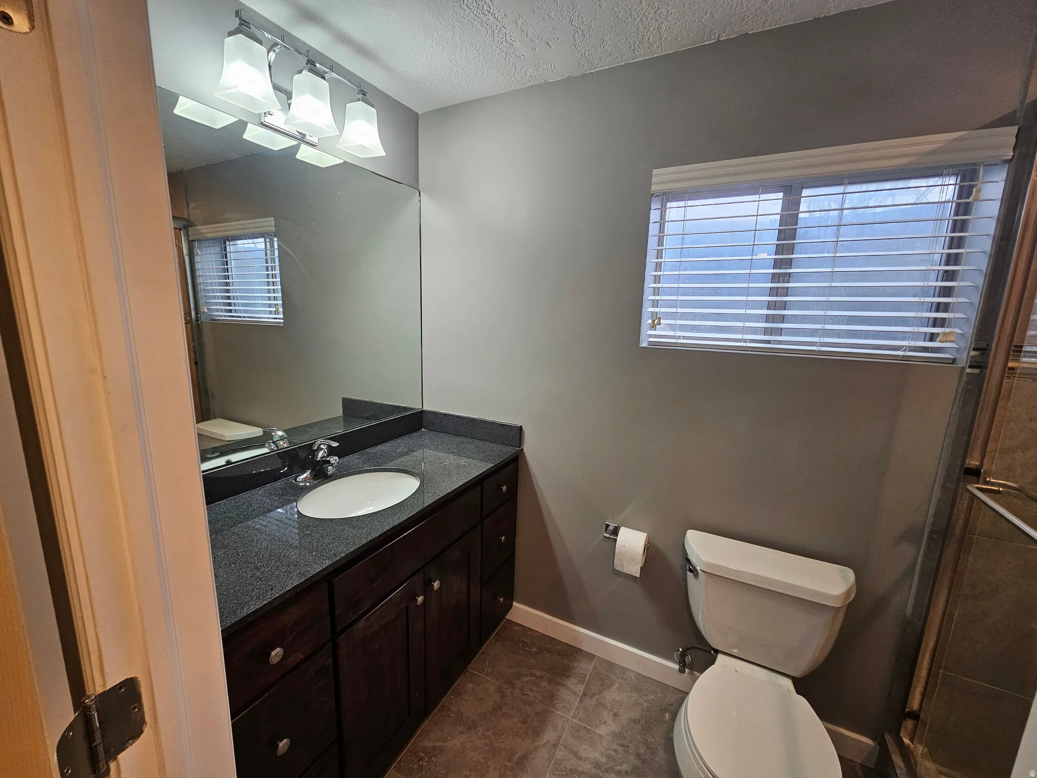 Bathroom with a dark wood-finish vanity, light-toned countertop, and a rectangular mirror