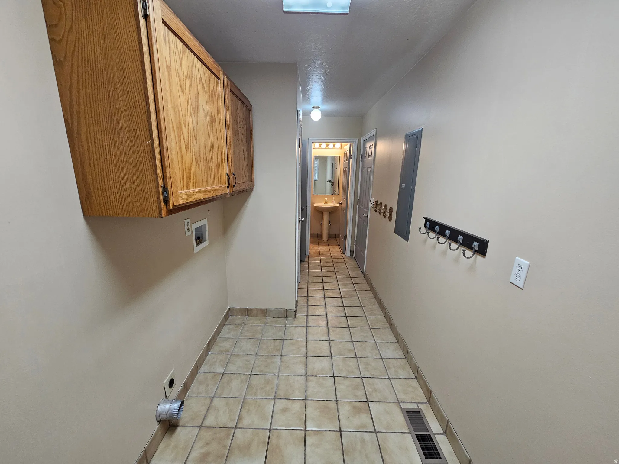 Laundry area featuring wood-finish cabinetry, tile flooring, and utility hookups