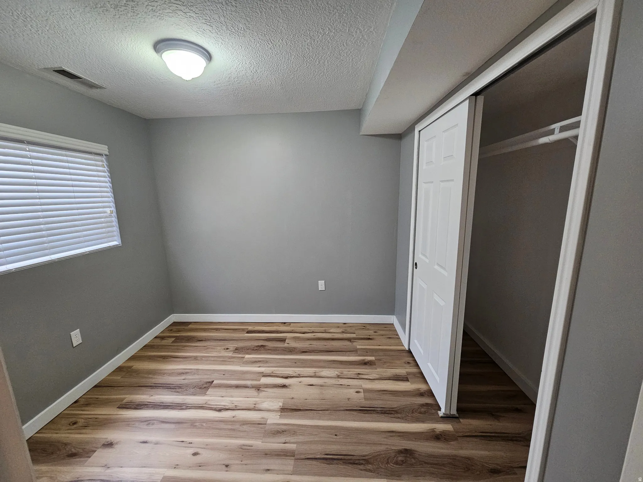 Room featuring wood-finish flooring, neutral gray wall tones, and white trim
