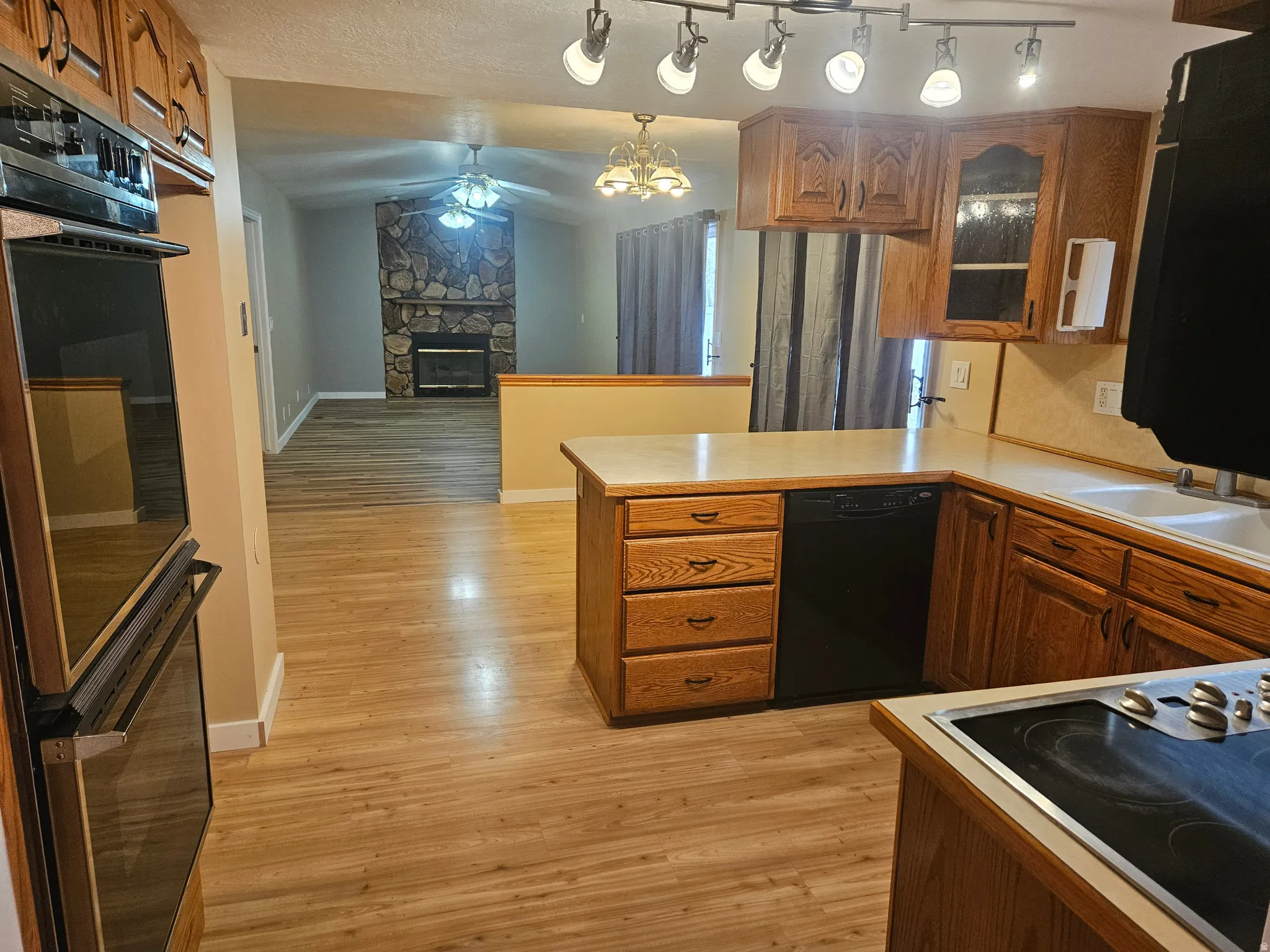 Kitchen featuring wood-finish flooring, built-in double oven, light-toned countertops, and wood cabinetry