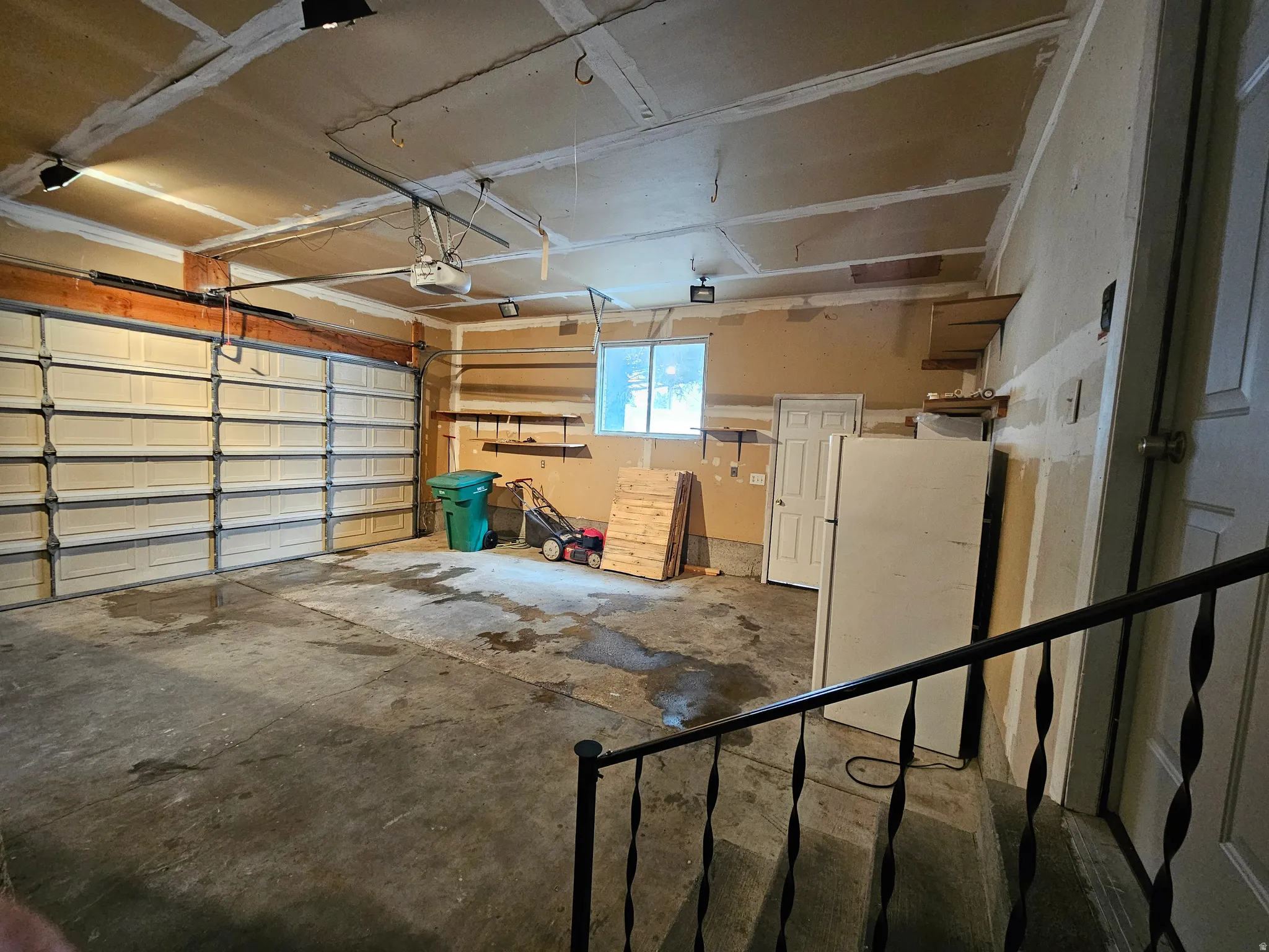 Spacious garage featuring a paneled overhead door, concrete flooring, overhead lighting, and built-in shelving
