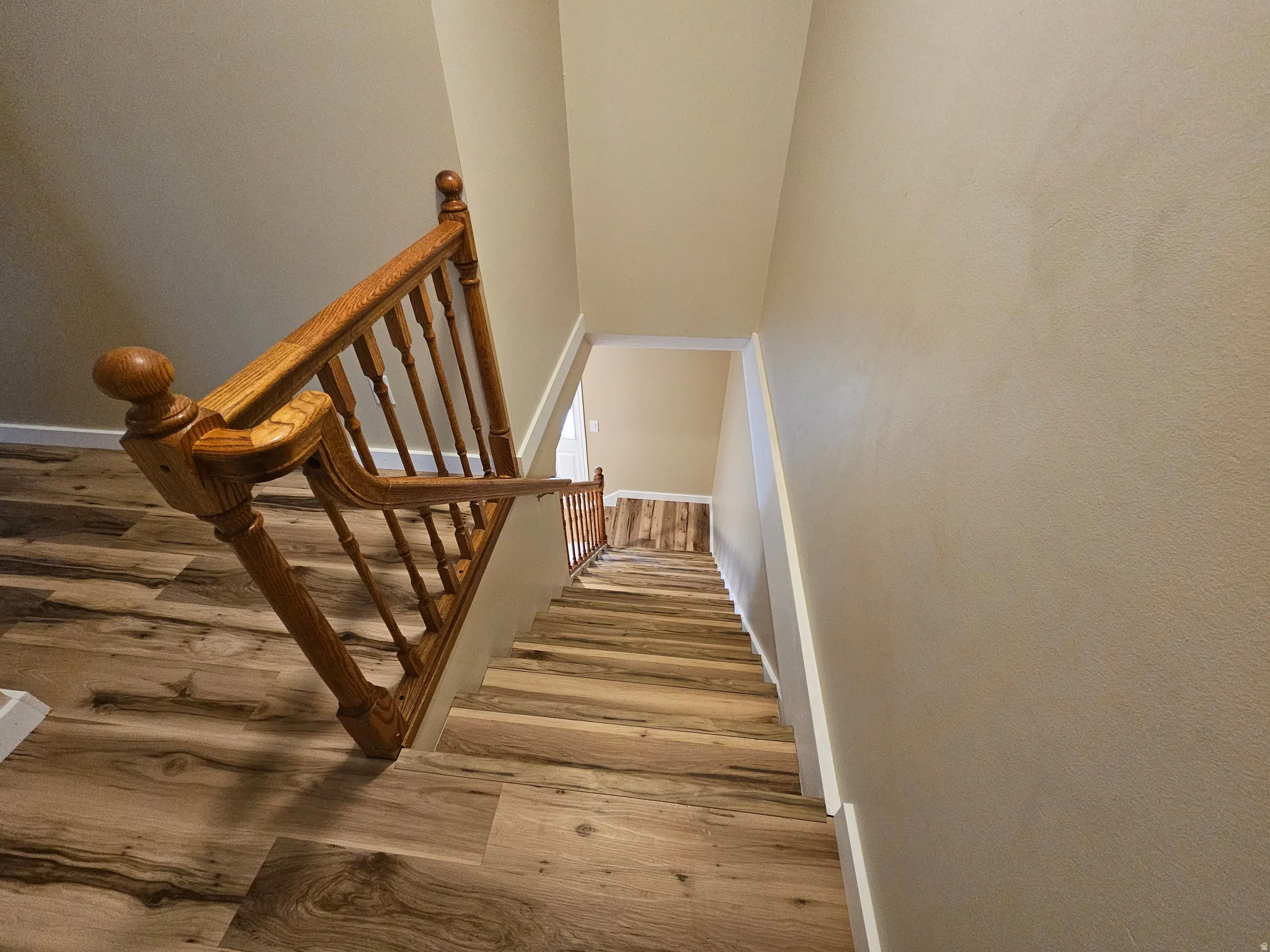 Staircase featuring wood-finish flooring, wood balusters, and a matching wood handrail