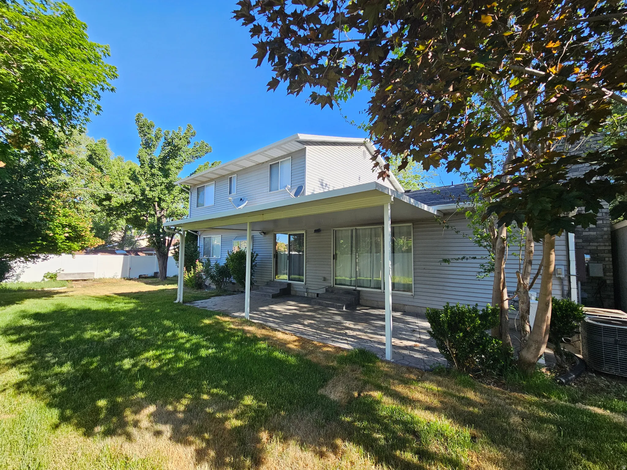 Expansive backyard featuring a covered patio, paved patio area, and mature trees