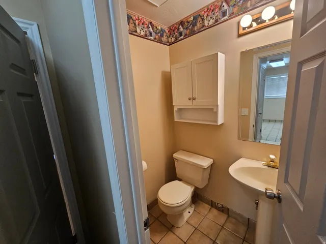 Powder room with a wall-mounted sink, ceramic tile flooring, and a wall-mounted storage cabinet