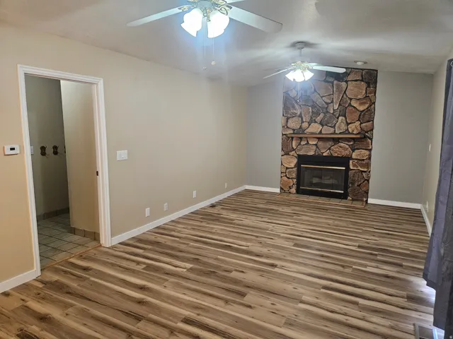 Spacious interior featuring wood-finish flooring, a stone-clad fireplace with a wood mantle, and neutral wall tones