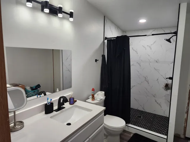 Bathroom featuring a contemporary vanity with a white countertop and integrated sink, a black single-handle faucet, and a rectangular mirror