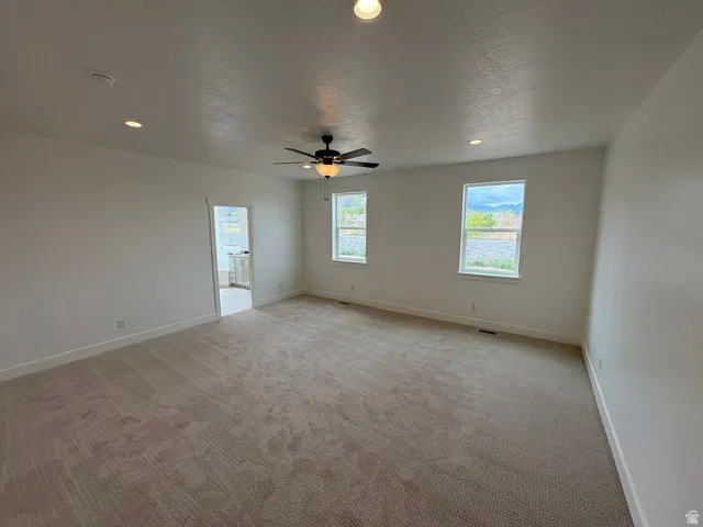 Spacious room with plush carpeting, recessed lighting, and a ceiling fan